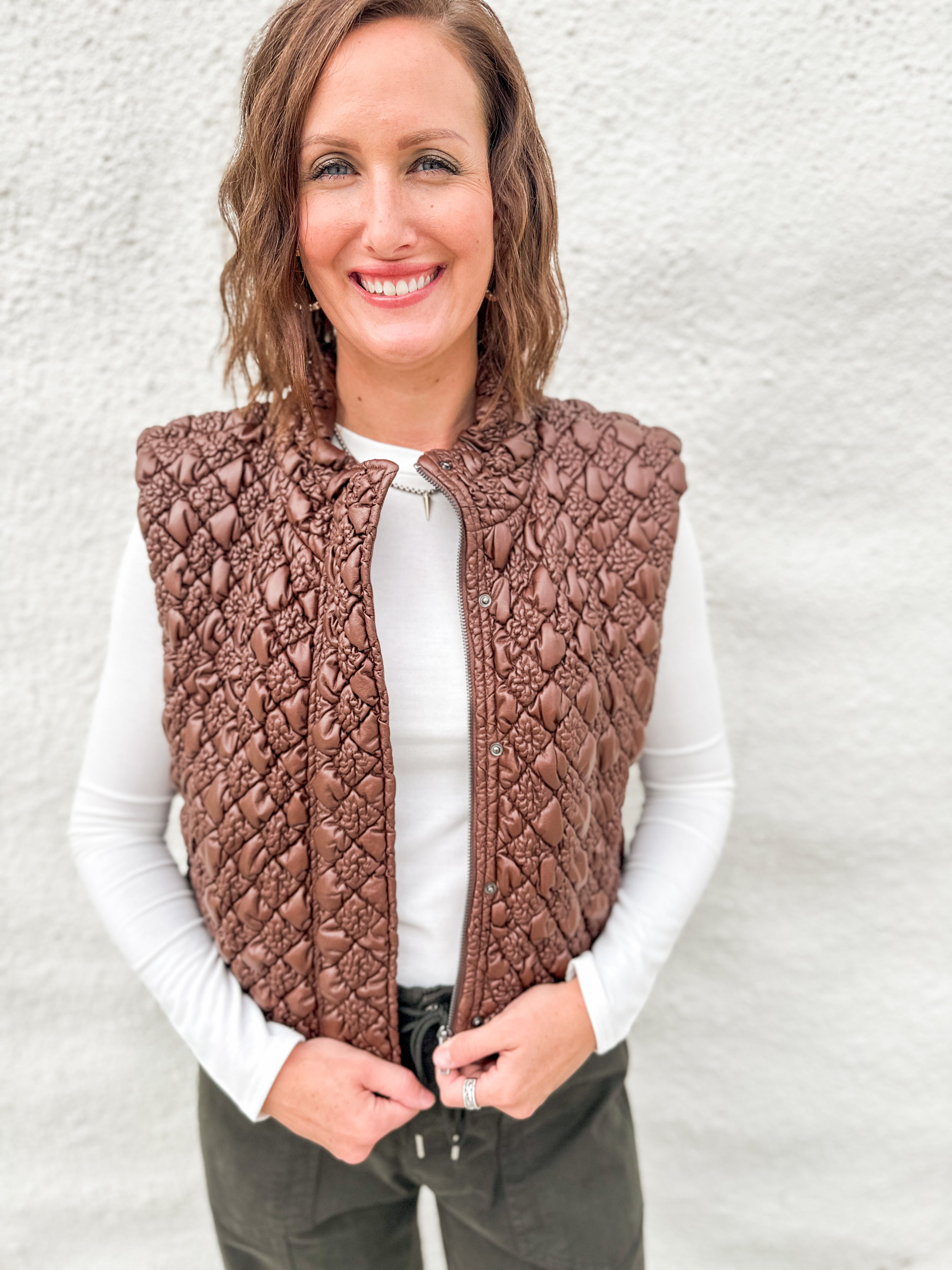 Model wearing a quilted brown vest with a faux leather look layered over a white ribbed long sleeve tee and green barrel denim from Daze