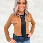 Model wearing a camel colored stretchy cropped denim jacket over a scuba black tee with asymmetrical lace hem detail and blue denim.