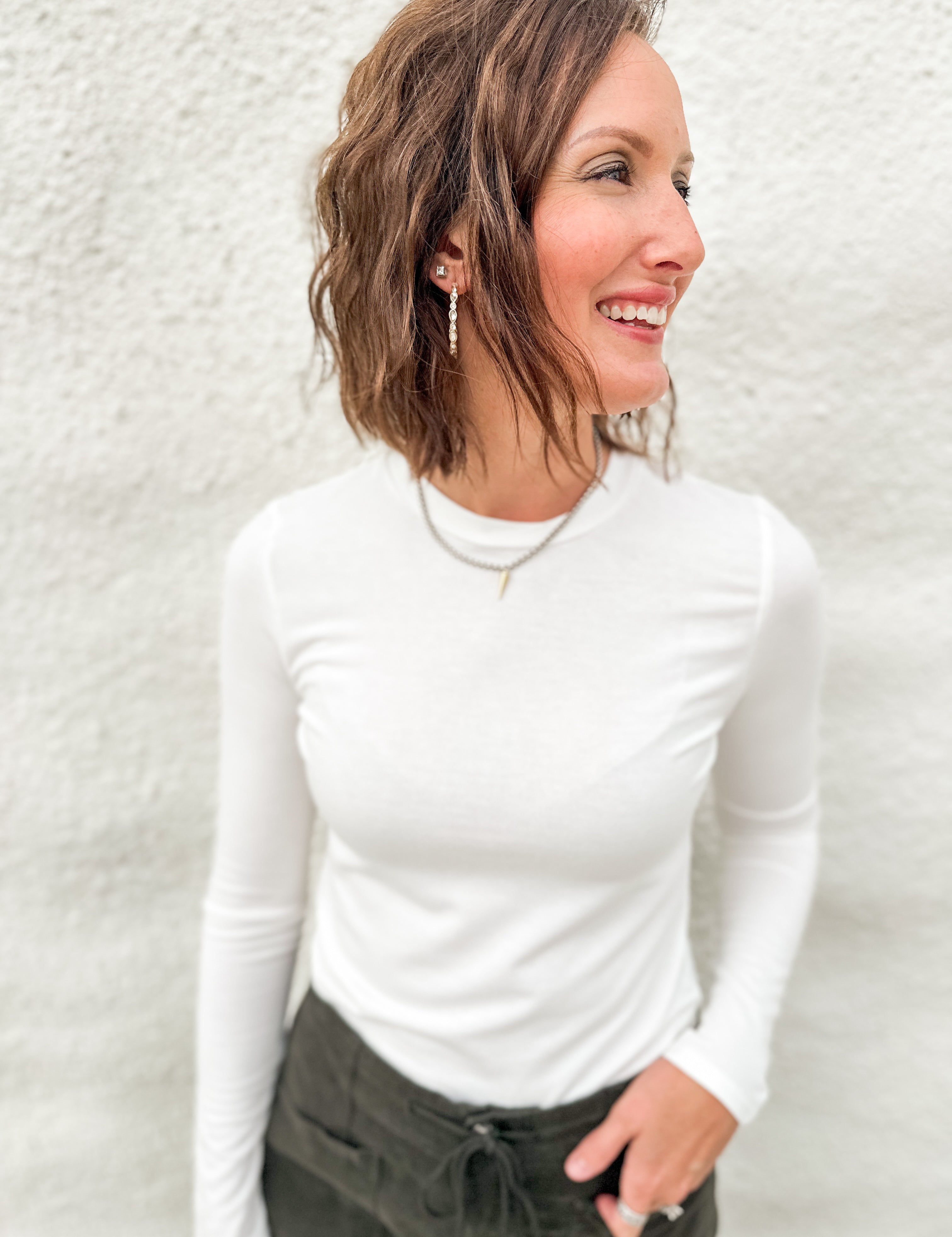 Woman wearing a soft lightly ribbed white long sleeved tee with green villa barrel jeans from Daze