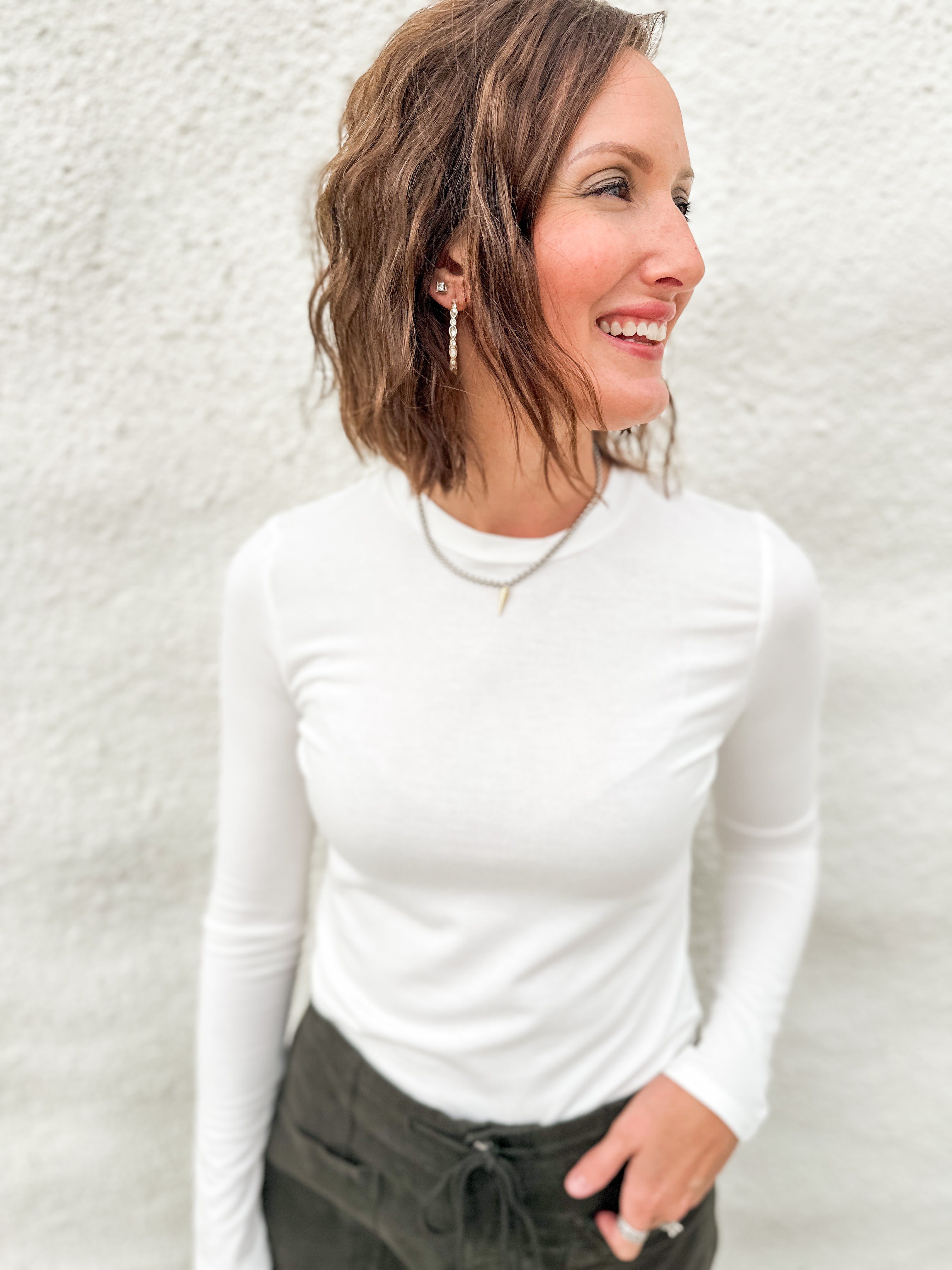 Woman wearing a soft lightly ribbed white long sleeved tee with green villa barrel jeans from Daze