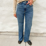 Woman wearing high rise wide leg denim with a raw hem, distressed black leather clogs and cream long sleeve top from Dear John