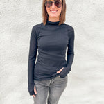 Model wearing a semi sheer ribbed black layering top from Free People with lettuce edge detailing
