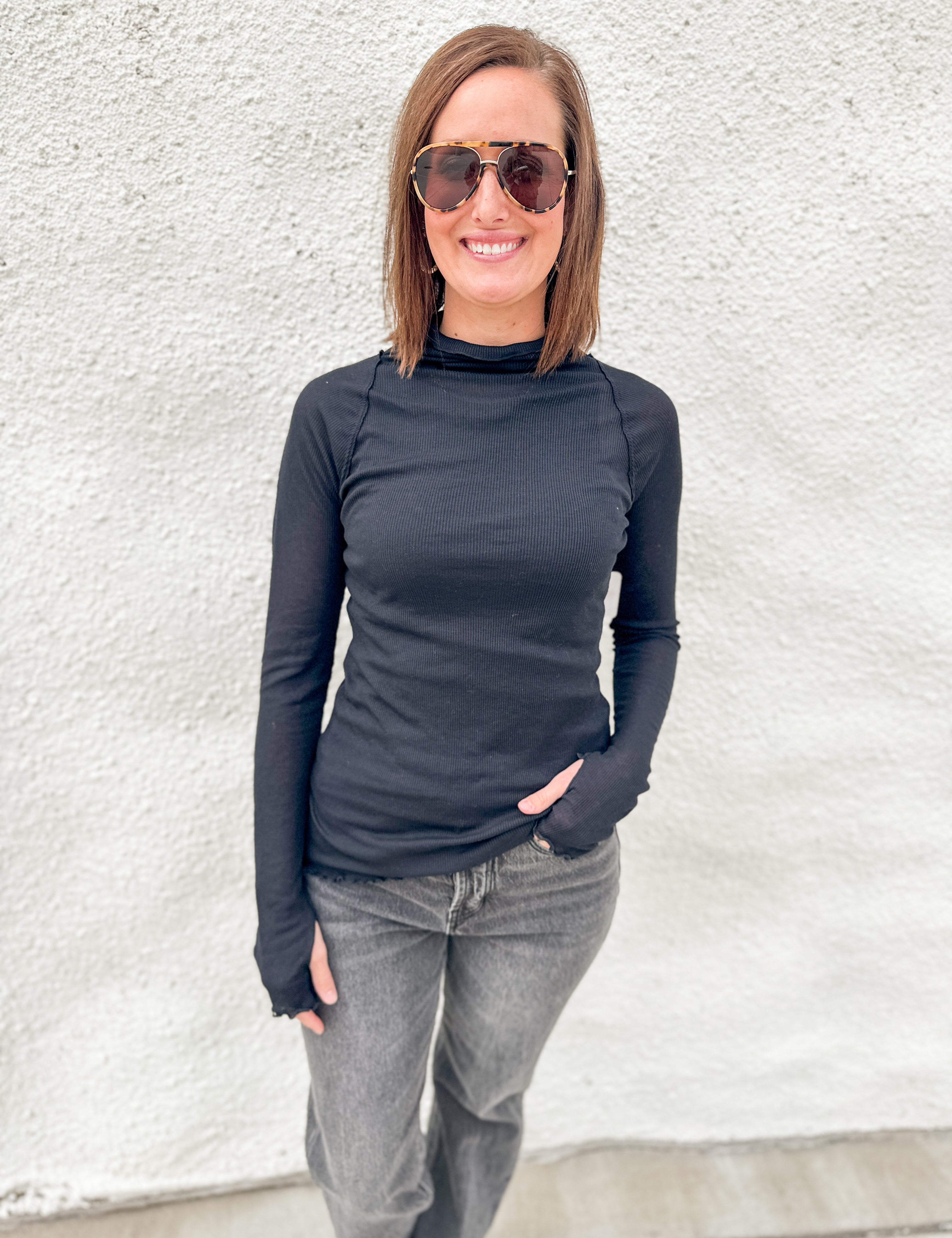 Model wearing a semi sheer ribbed black layering top from Free People with lettuce edge detailing