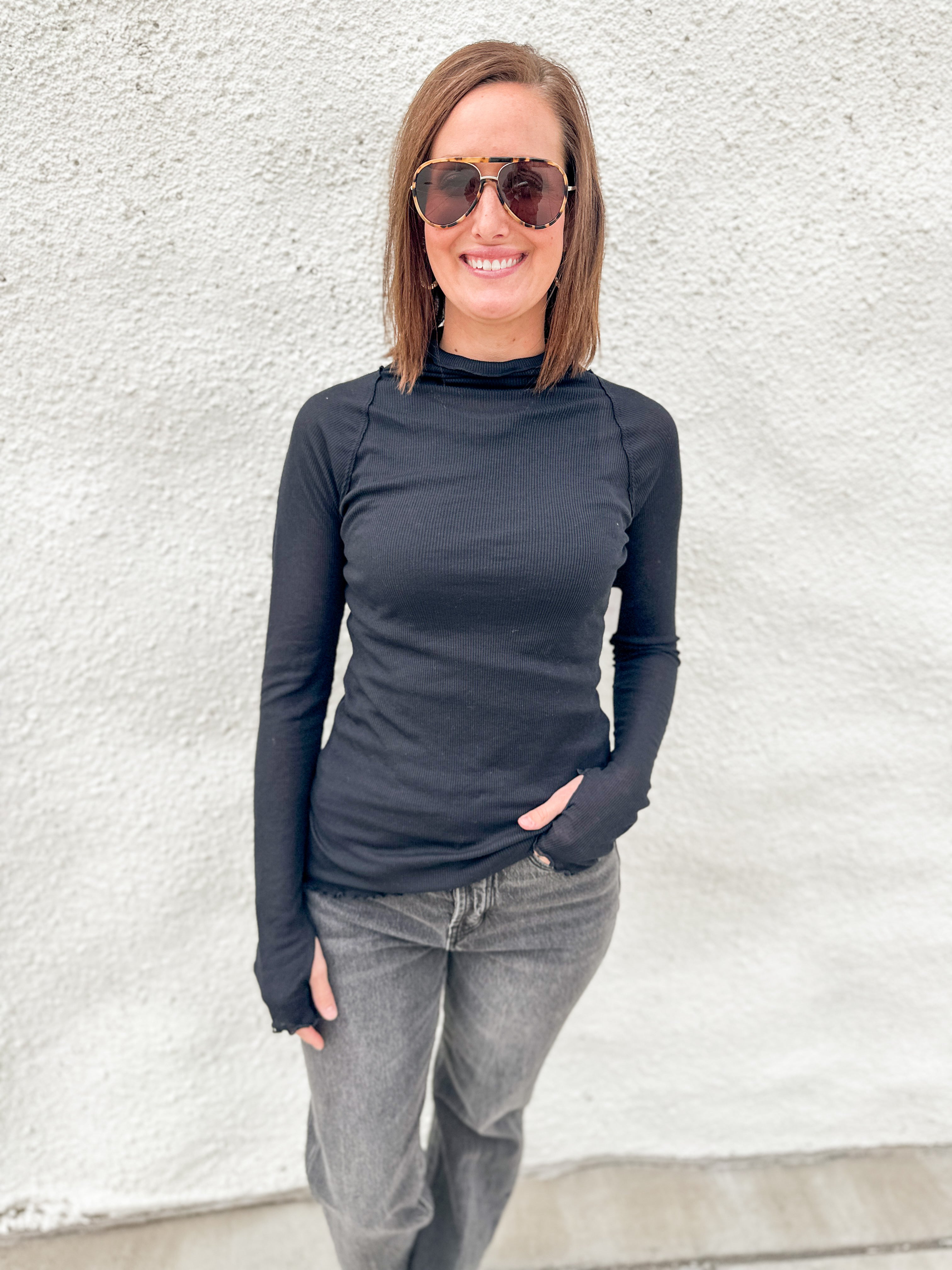 Model wearing a semi sheer ribbed black layering top from Free People with lettuce edge detailing