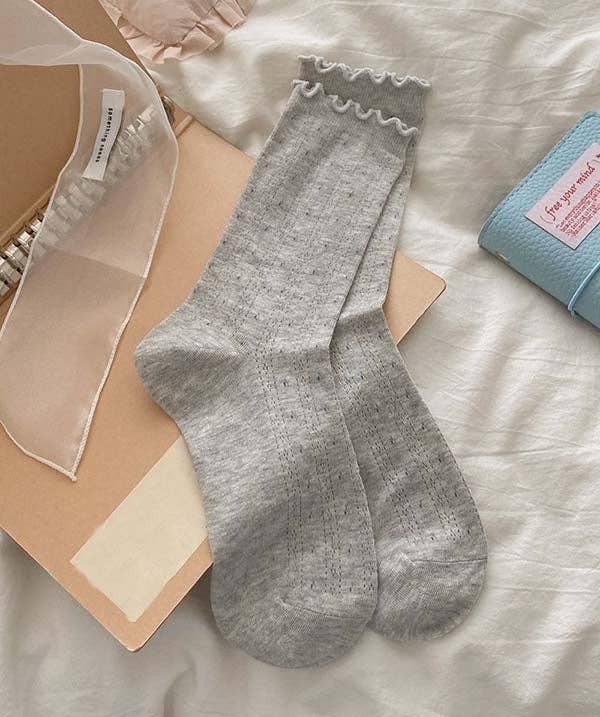 Gray socks with ruffled top and delicate floral pattern on a light background