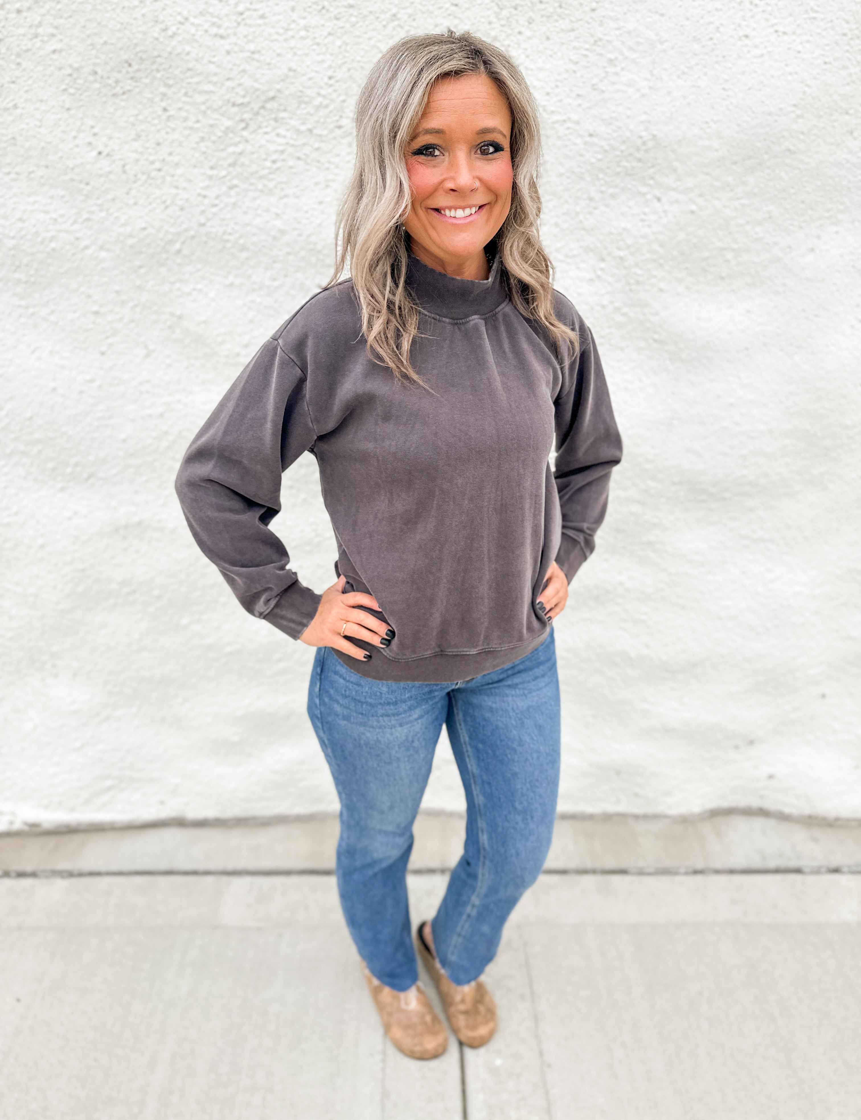 Model wearing a washed espresso colored mockneck sweatshirt with straight leg denim and faux snakeskin clogs with gold studs