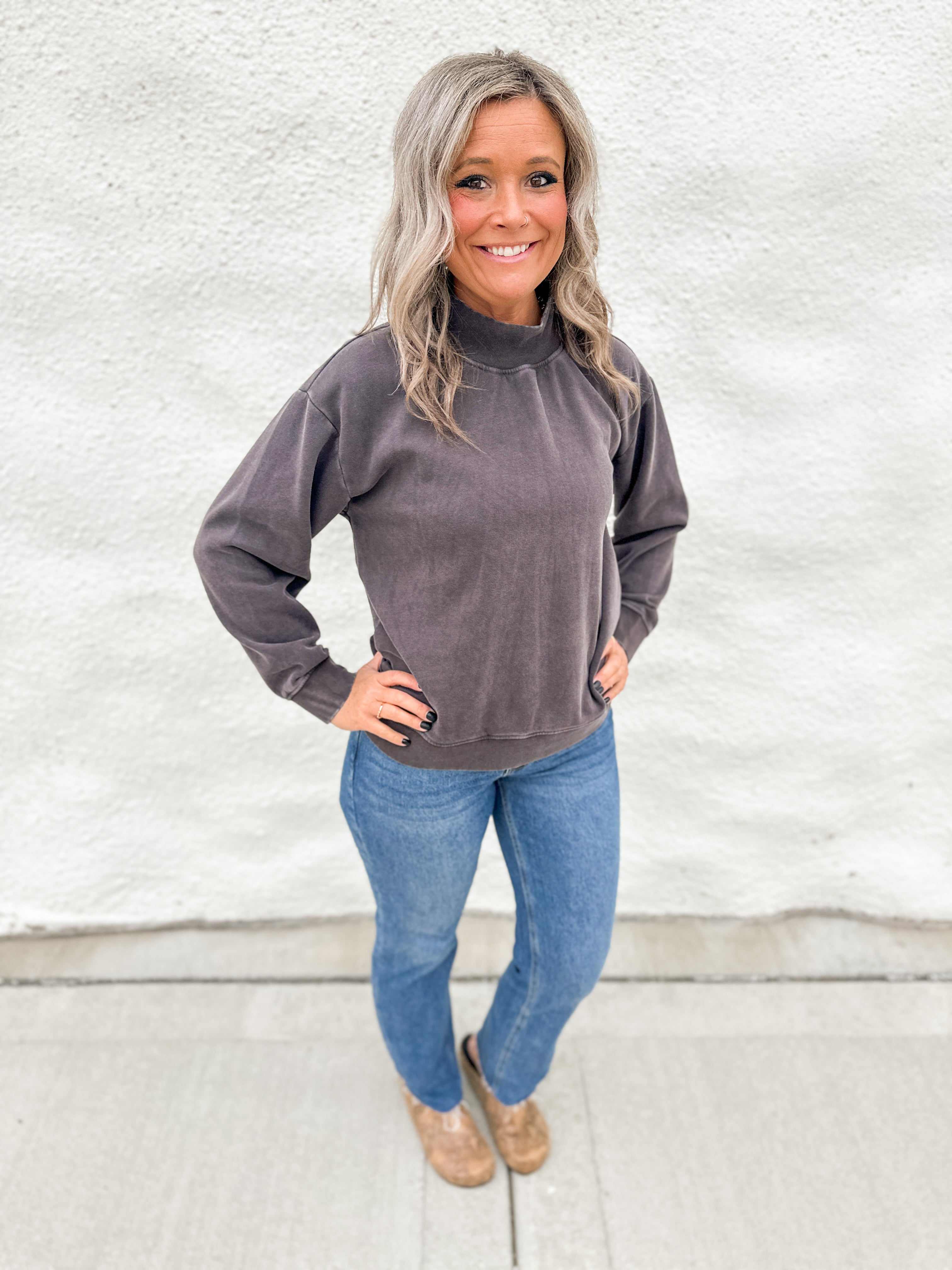 Model wearing a washed espresso colored mockneck sweatshirt with straight leg denim and faux snakeskin clogs with gold studs