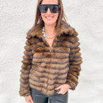 Faux fur jacket with silver zippered front, tiered textured layers of brown fur with dark brown tips, button cuff sleeve detail on model