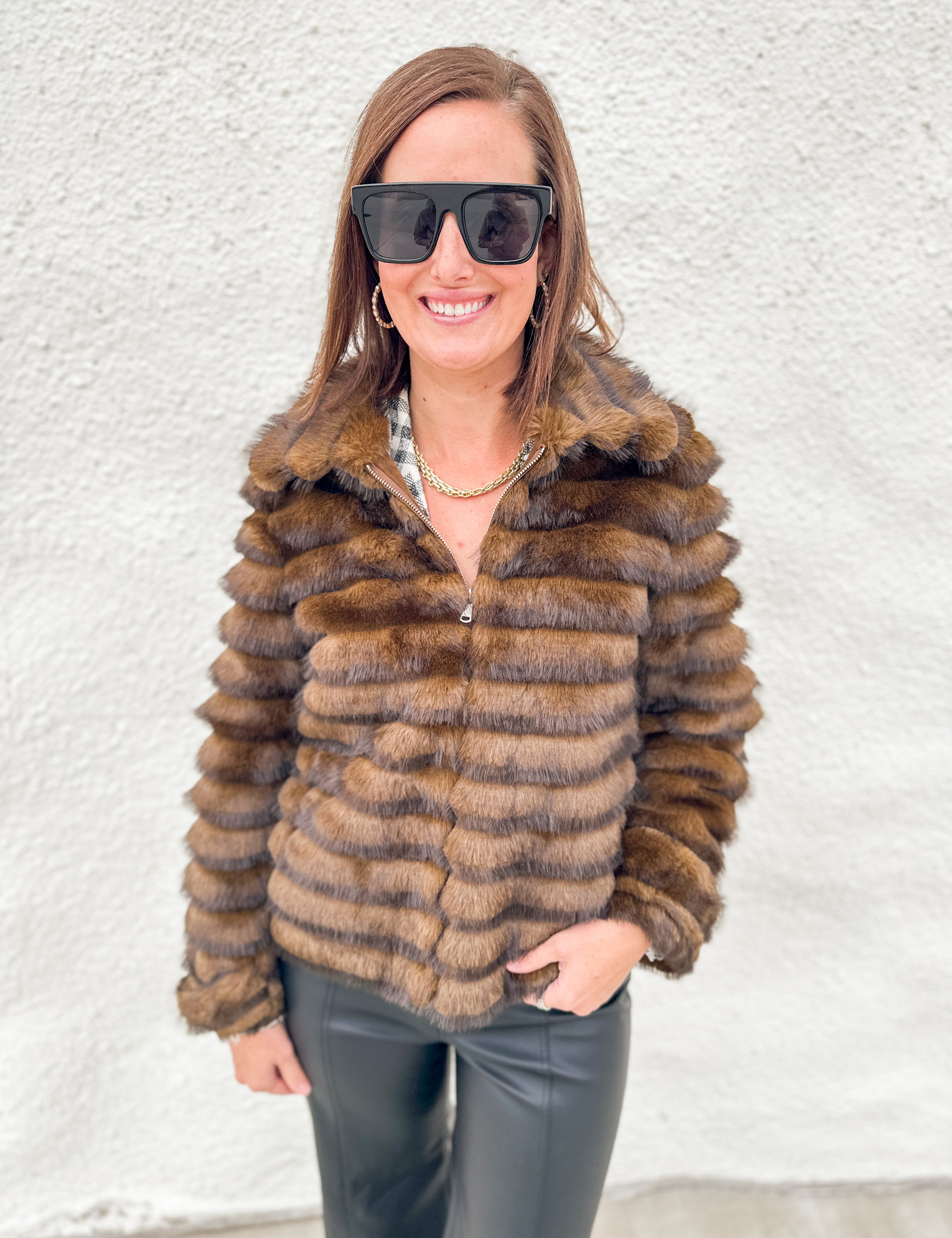 Faux fur jacket with silver zippered front, tiered textured layers of brown fur with dark brown tips, button cuff sleeve detail on model