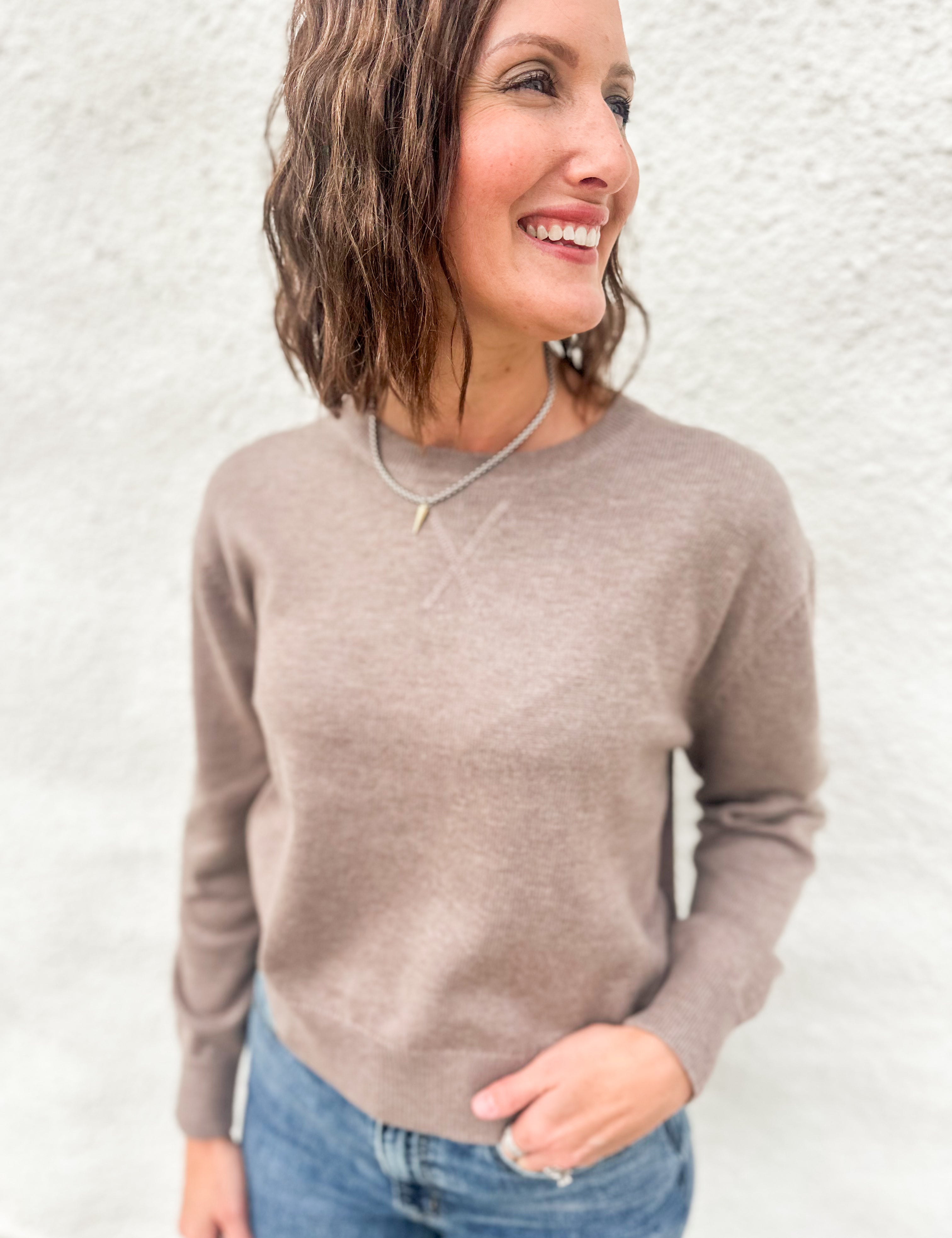 Model wearing a mocha colored lightweight crewneck sweater with wool blend, stitched v detail at neckline