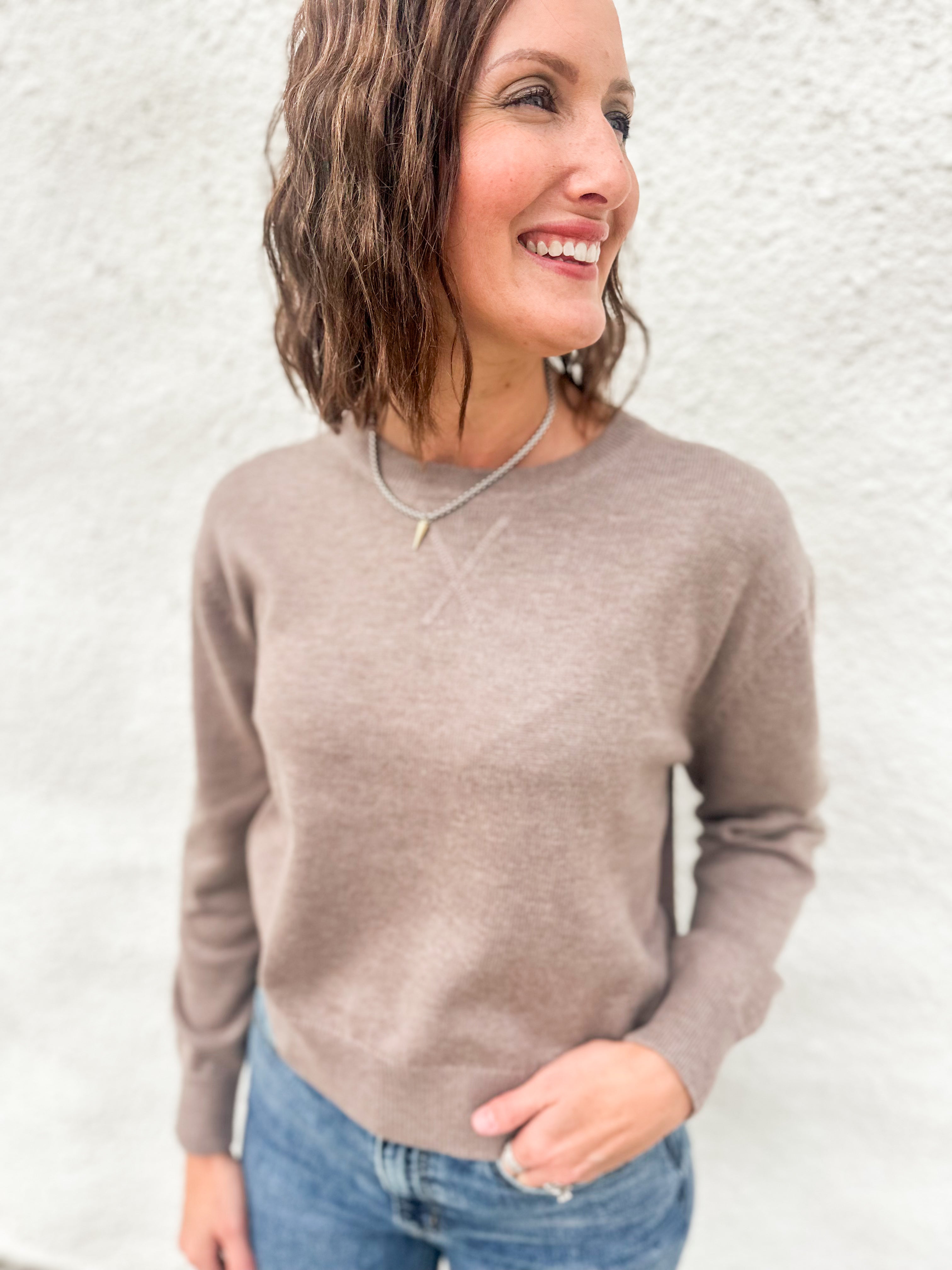 Model wearing a mocha colored lightweight crewneck sweater with wool blend, stitched v detail at neckline