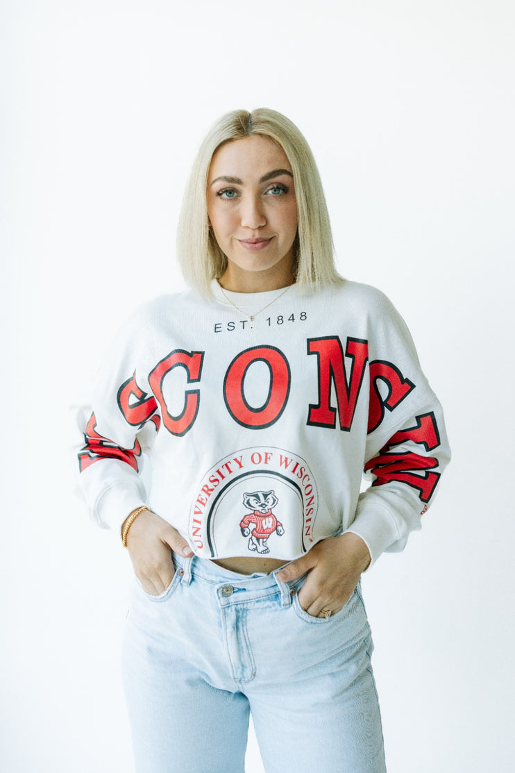 Person wearing a white sweatshirt with red text and a logo, standing against a white background