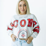 Person wearing a white sweatshirt with red text and a logo, standing against a white background