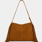 A camel brown suede shoulder bag with long fringe detailing on the sides and a thin matching shoulder strap, shown against a plain light gray background.