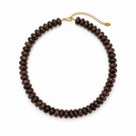 A dark brown beaded necklace made of small, polished disc-like beads, featuring a gold-tone chain extender clasp with a small tag, displayed on a clean white background.